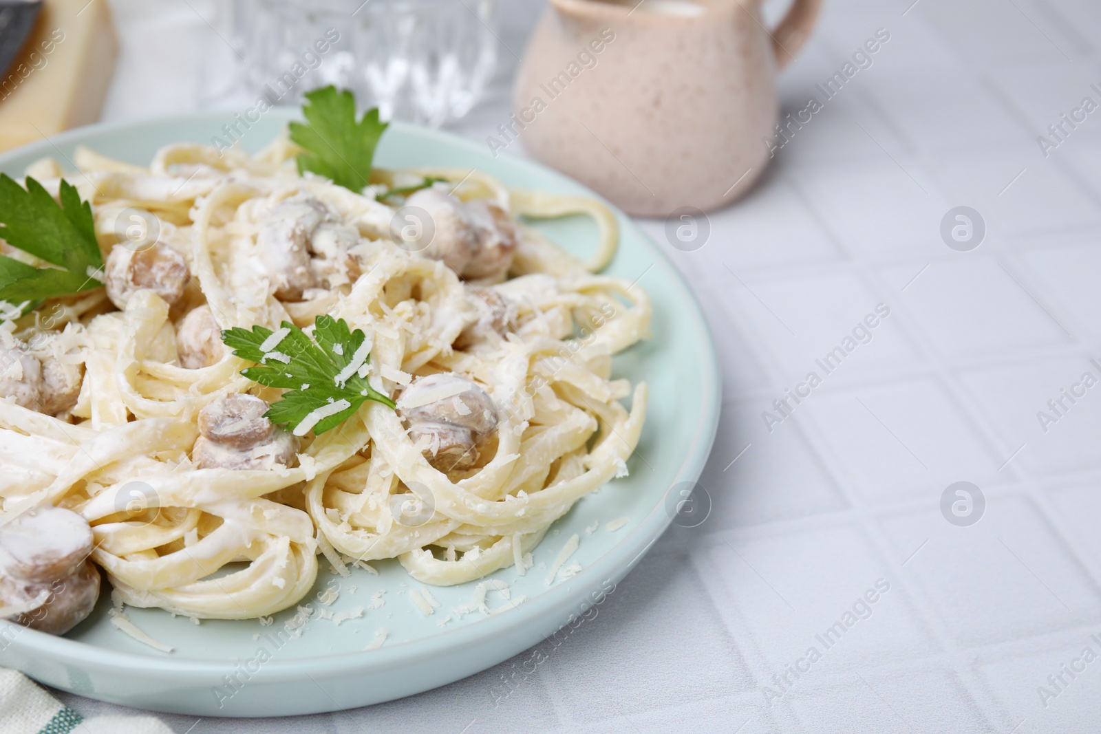 Photo of Delicious pasta with mushrooms on white tiled table, closeup