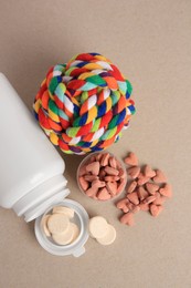 Photo of Different pet vitamins and toy on beige background, flat lay