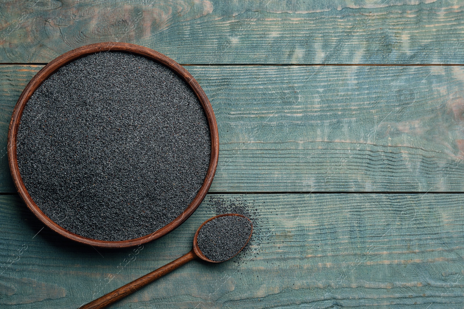 Photo of Poppy seeds in bowl and spoon on blue wooden table, flat lay. Space for text