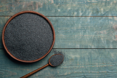 Photo of Poppy seeds in bowl and spoon on blue wooden table, flat lay. Space for text