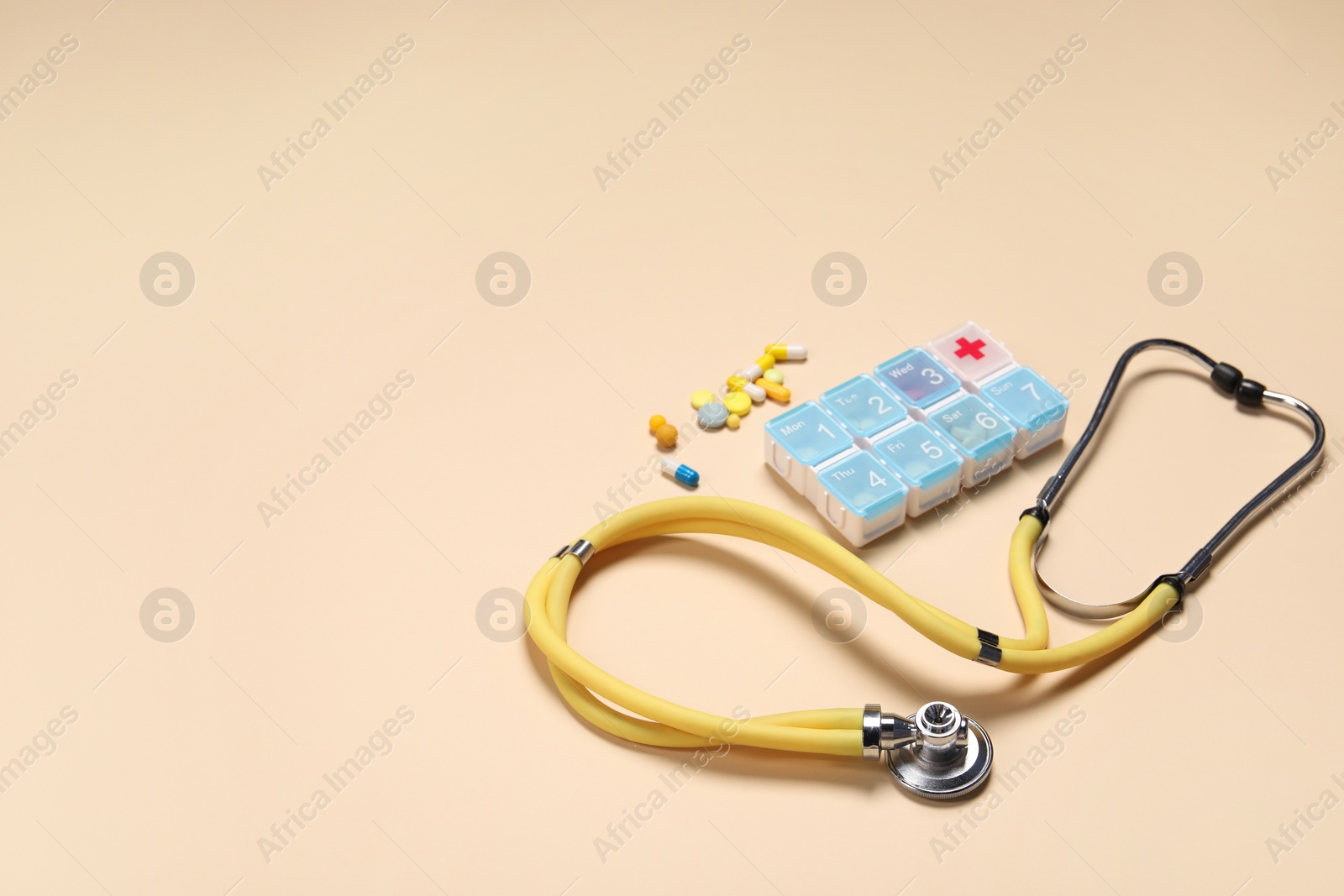 Photo of Stethoscope and pills on beige background. Space for text