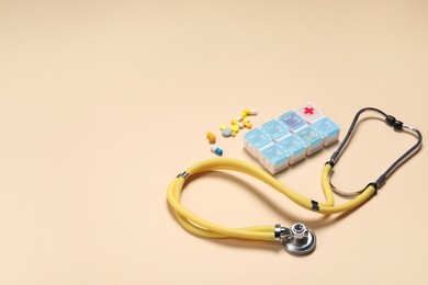 Photo of Stethoscope and pills on beige background. Space for text