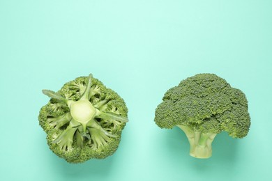 Photo of Fresh tasty broccoli on turquoise background, flat lay