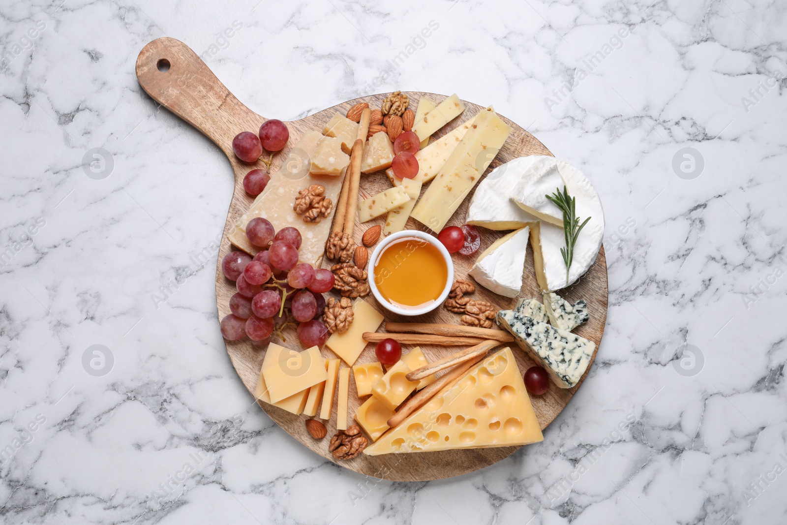 Photo of Cheese plate with honey, grapes and nuts on white marble table, top view