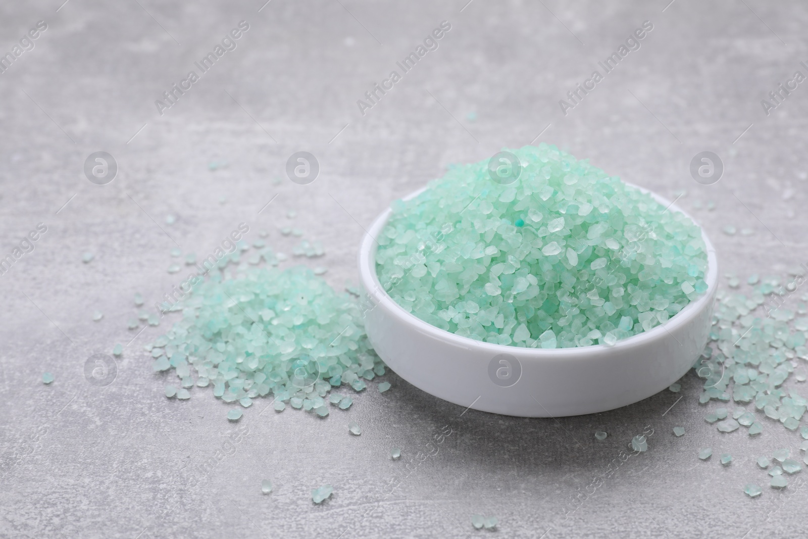 Photo of Plate with turquoise sea salt on light grey table. Space for text