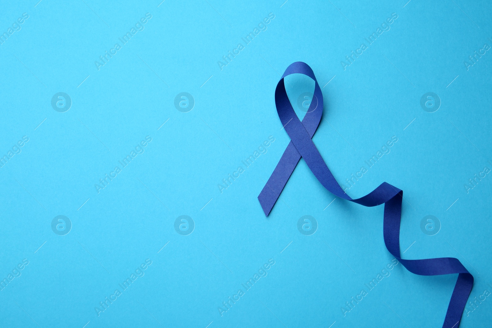 Photo of Blue awareness ribbon on color background, top view with space for text. Symbol of social and medical issues