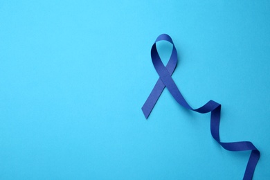 Photo of Blue awareness ribbon on color background, top view with space for text. Symbol of social and medical issues