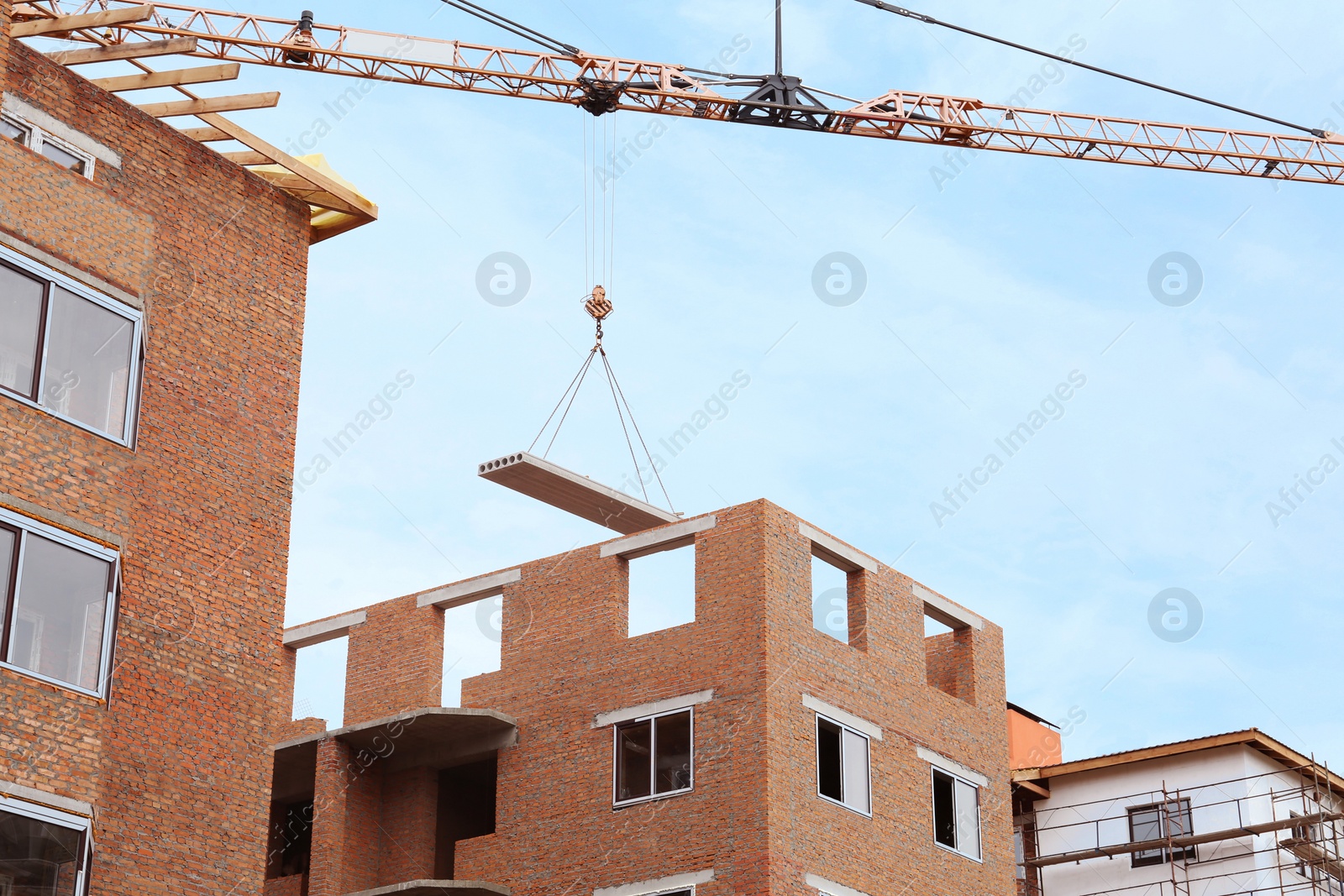 Photo of Construction site with tower crane near unfinished building, low angle view