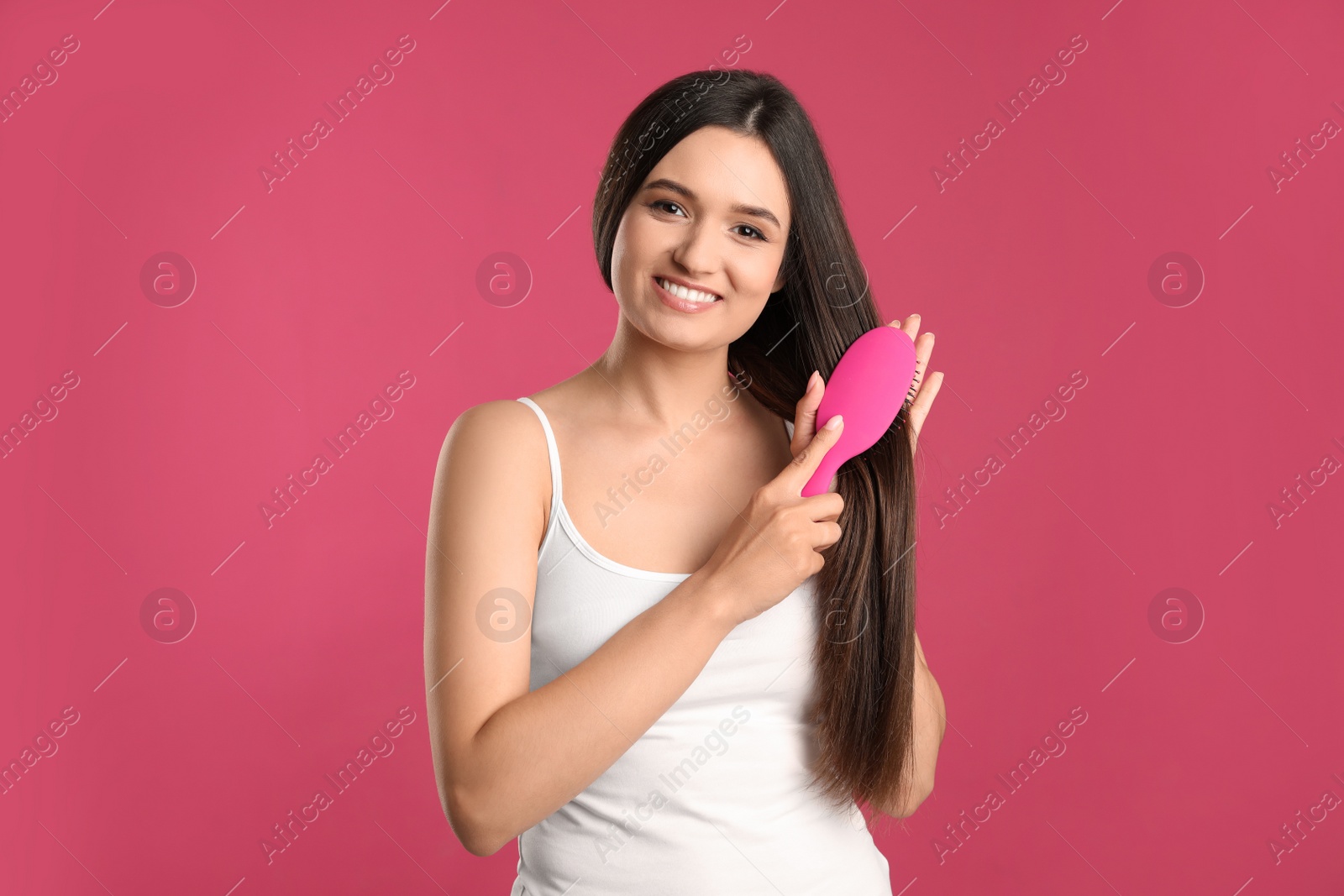 Photo of Beautiful smiling young woman with hair brush on color background