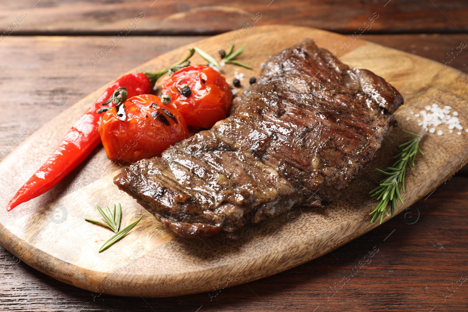 Photo of Delicious roasted beef meat, vegetables and spices on wooden table, closeup