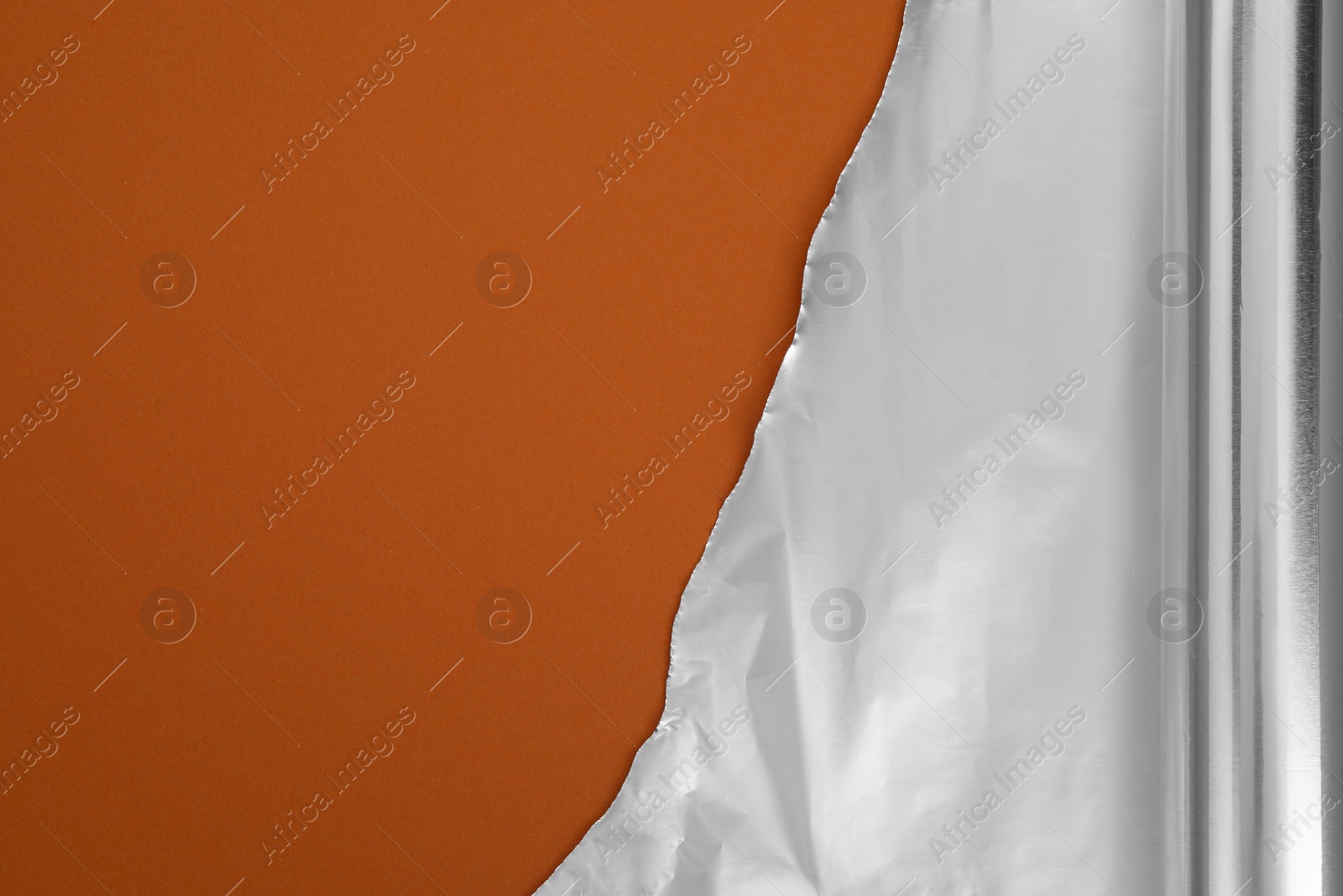 Photo of One roll of aluminum foil on brown background, top view. Space for text