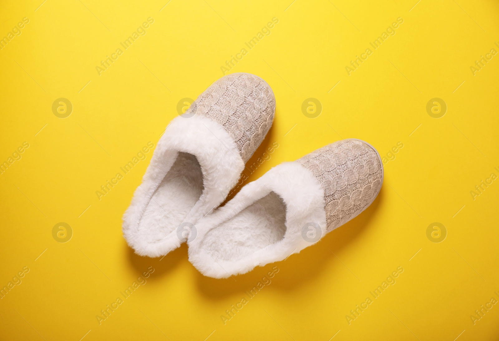 Photo of Pair of beautiful soft slippers on yellow background, top view