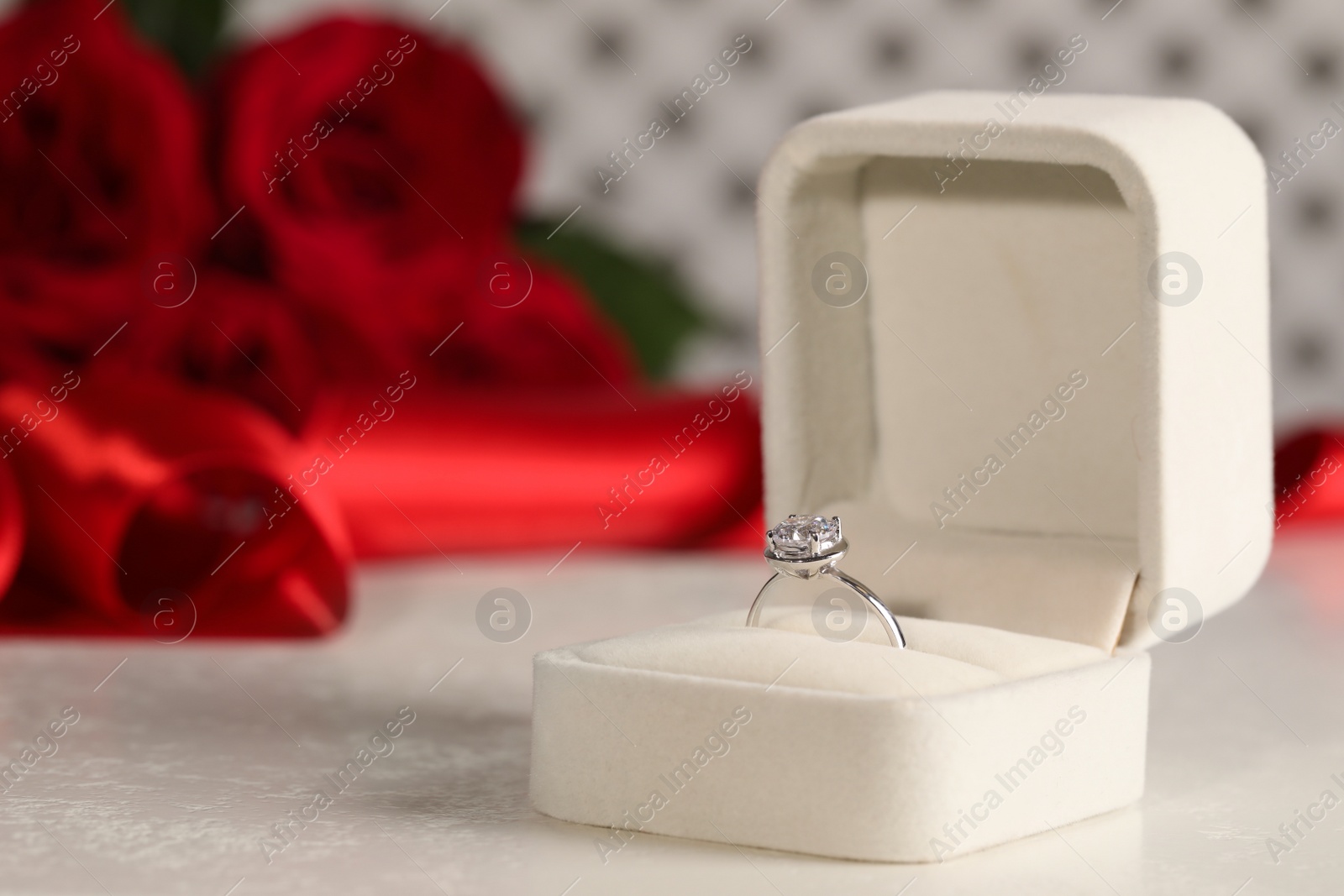 Photo of Beautiful engagement ring with gemstone in box on white table. Space for text