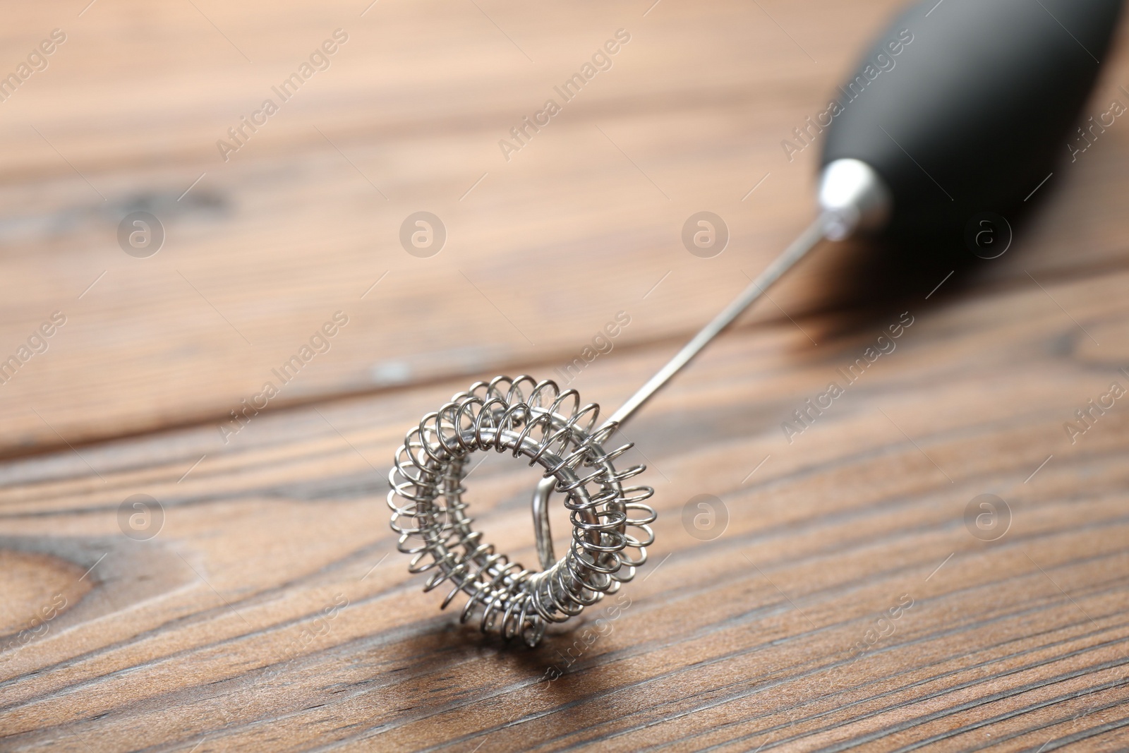 Photo of Black milk frother wand on wooden table, closeup. Space for text