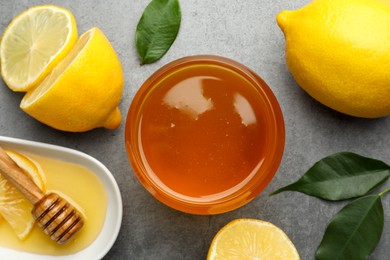 Photo of Sweet honey and fresh lemons on grey table, flat lay