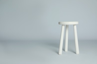 Photo of Stylish wooden stool on light grey background. Space for text