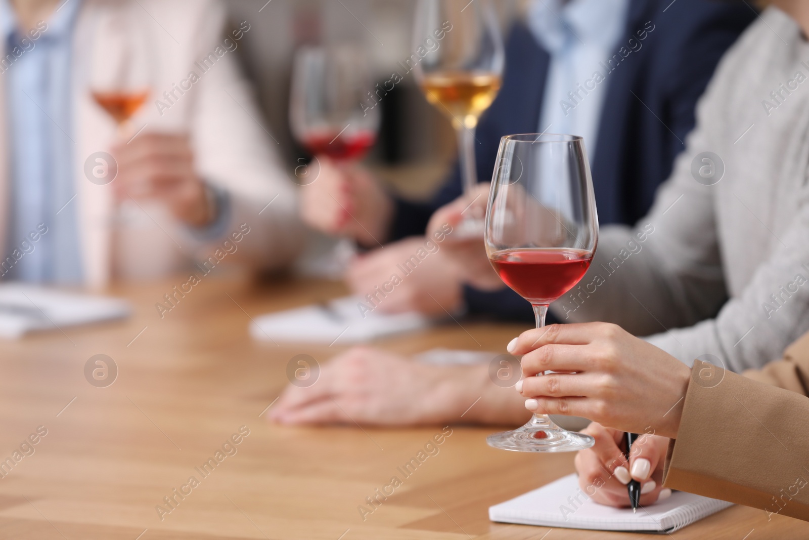 Photo of Sommeliers tasting different sorts of wine at table indoors, closeup