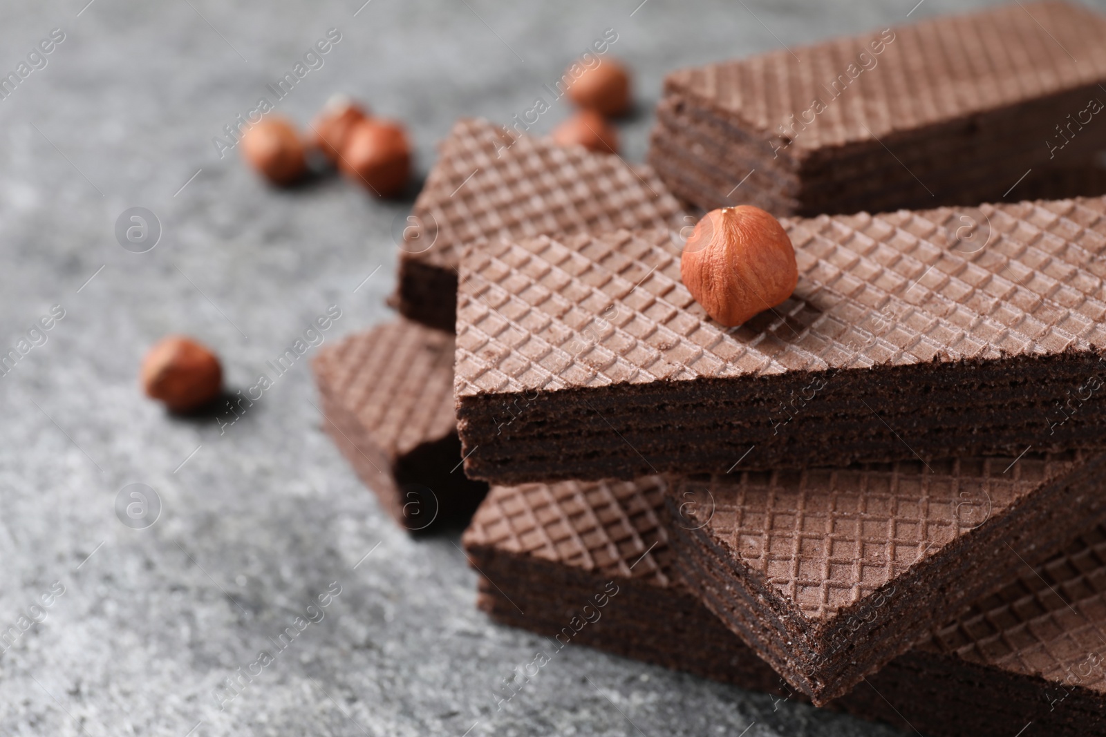 Photo of Delicious chocolate wafers and hazelnuts on grey table, closeup. Space for text