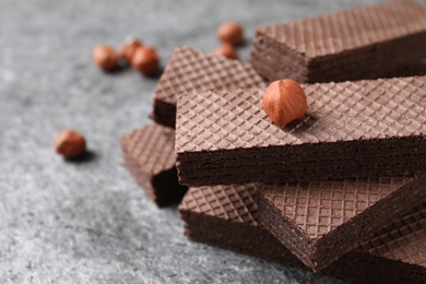 Delicious chocolate wafers and hazelnuts on grey table, closeup. Space for text