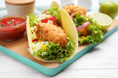 Delicious fish tacos served on white wooden table, closeup