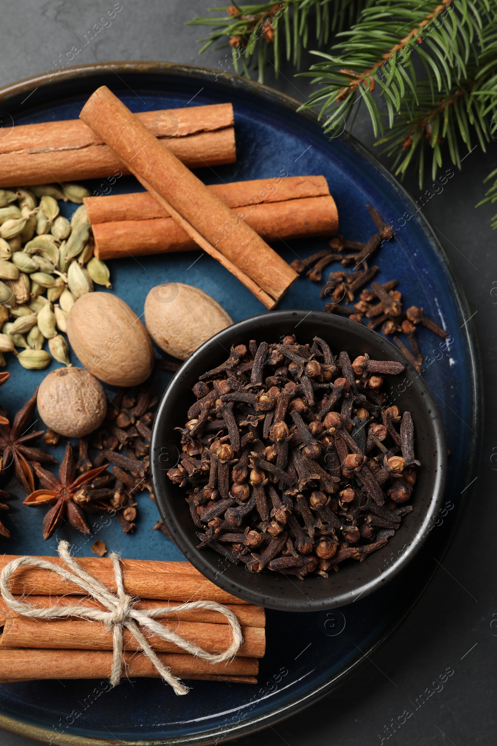 Photo of Dishware with different spices, nuts and fir branches on table, flat lay