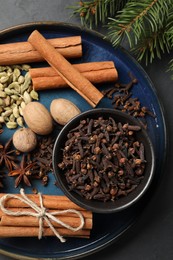 Dishware with different spices, nuts and fir branches on table, flat lay