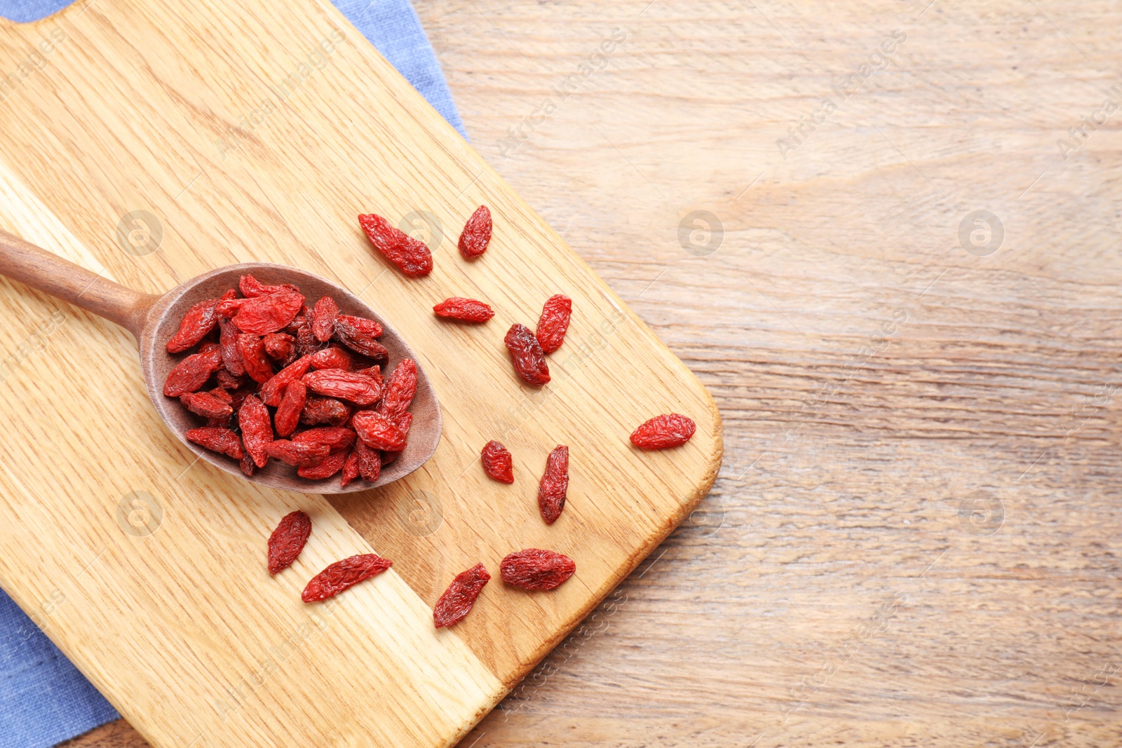 Photo of Dried goji berries on wooden table, flat lay. Space for text