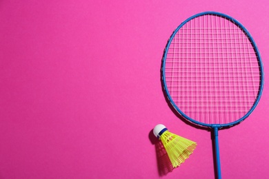 Photo of Badminton racket and shuttlecock on pink background, flat lay. Space for text