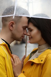 Lovely young couple with umbrella on city street