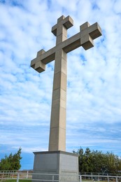 Big old cross under blue cloudy sky, low angle view