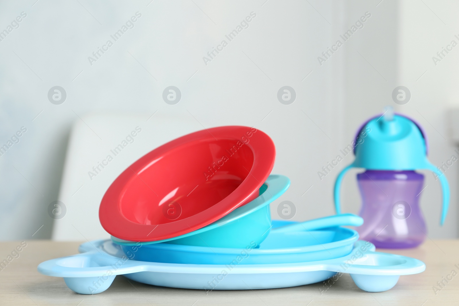 Photo of Set of plastic dishware on wooden table indoors. Serving baby food