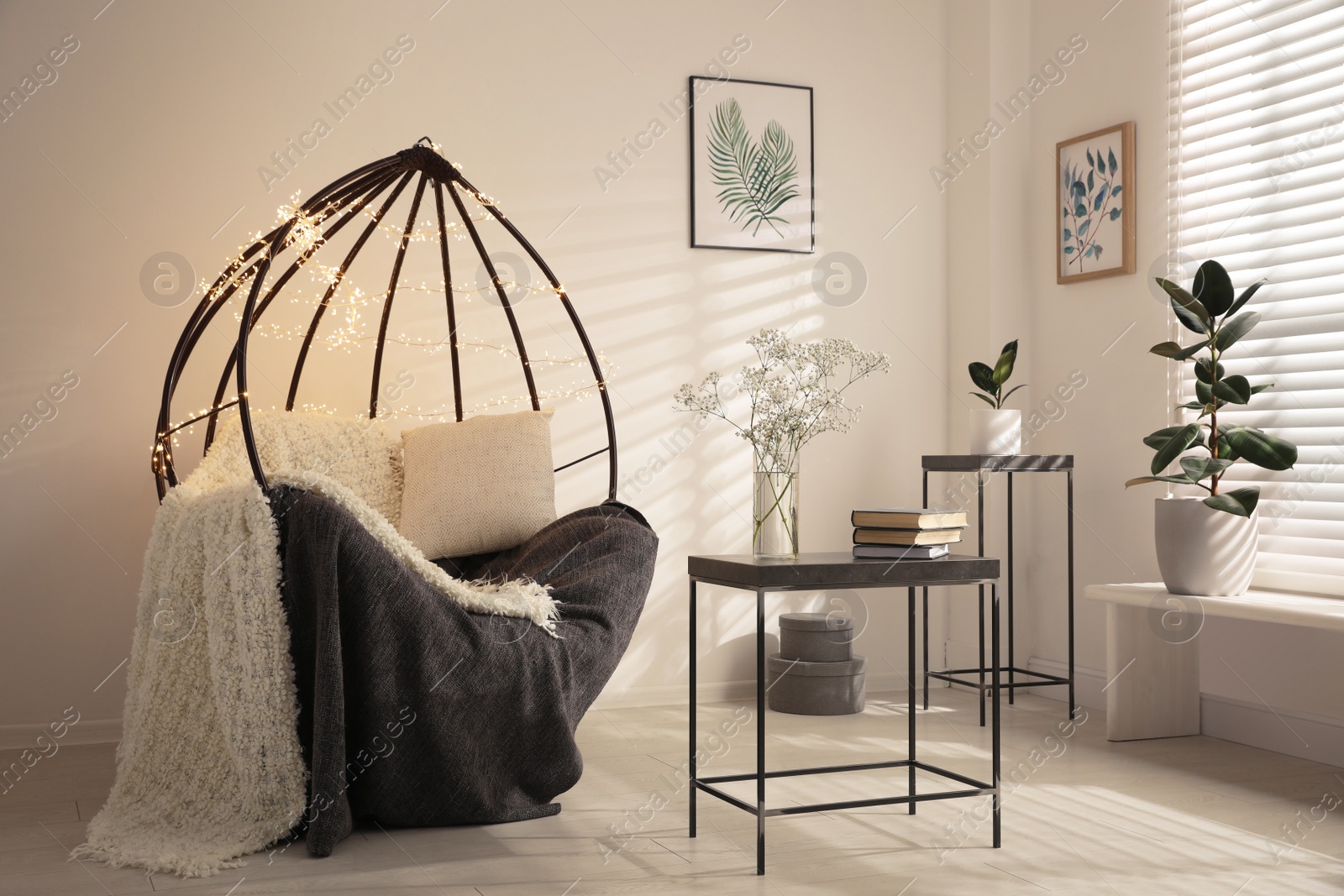 Photo of Cozy hanging chair with fairy lights in modern living room. Interior design