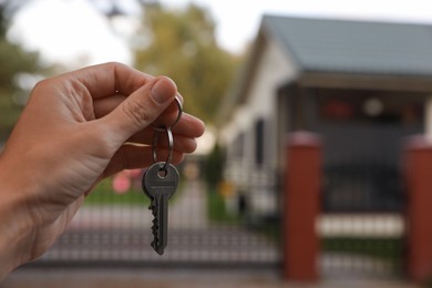 Real estate agent holding keys to new house outdoors, closeup. Space for text