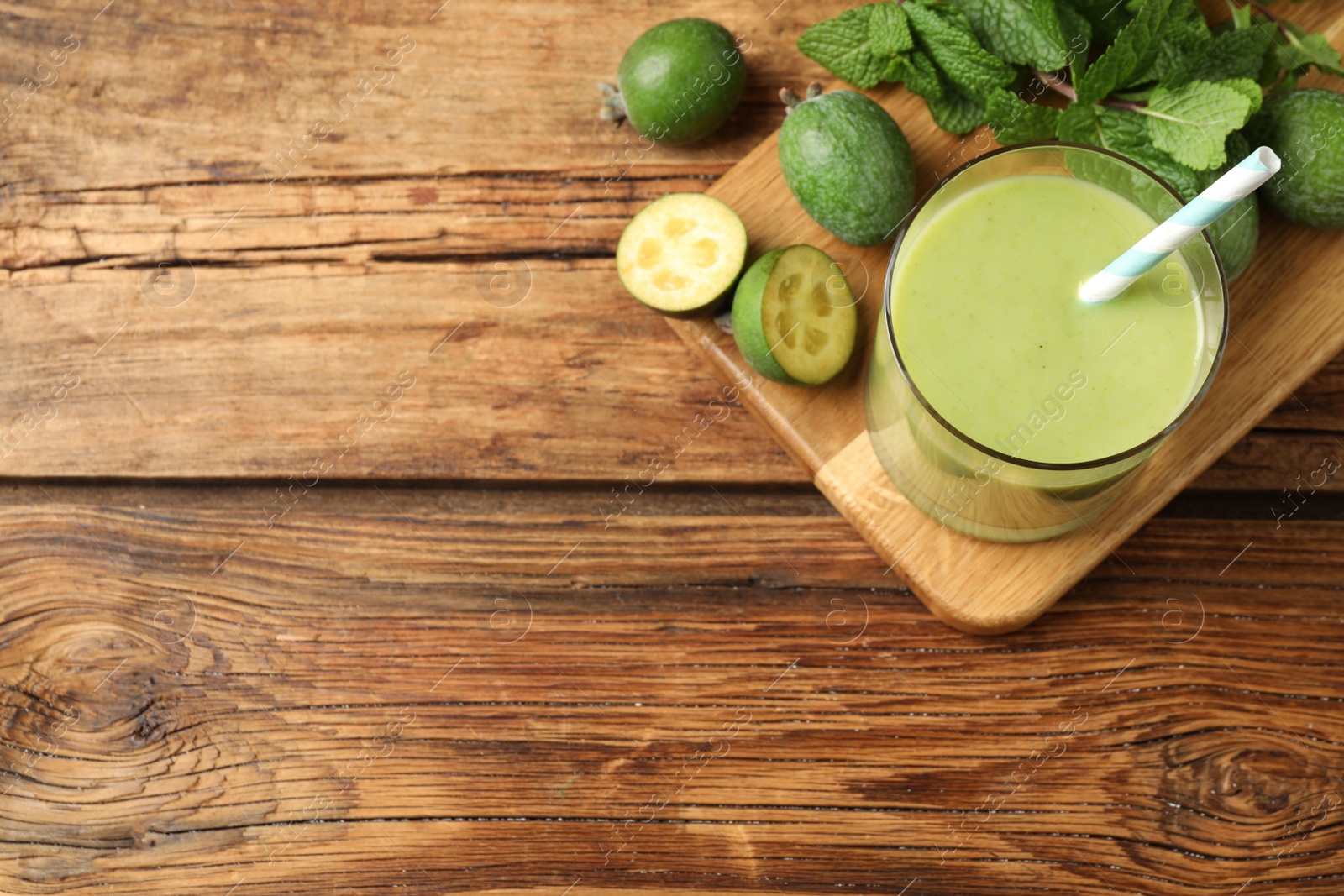 Photo of Fresh feijoa smoothie and ingredients on wooden table, flat lay. Space for text