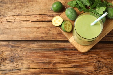 Fresh feijoa smoothie and ingredients on wooden table, flat lay. Space for text