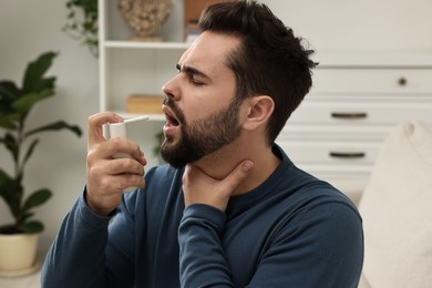 Photo of Young man using throat spray at home