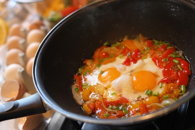 Cooking tasty eggs with vegetables in frying pan, closeup