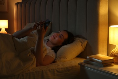 Woman using smartphone in bed at night. Internet addiction