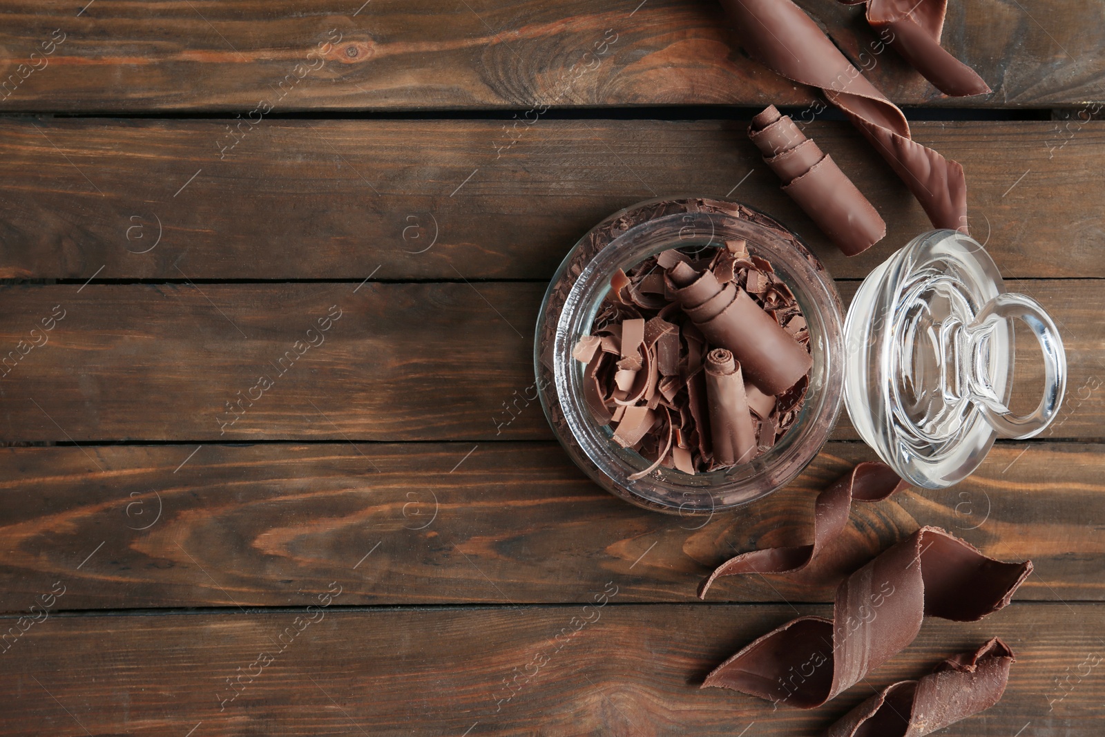 Photo of Flat lay composition with jar of chocolate curls on wooden background. Space for text