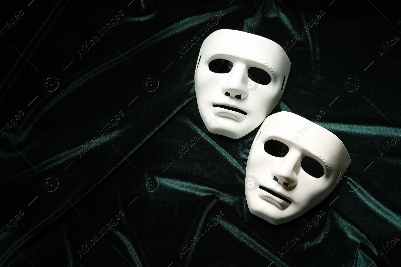 Photo of Theater arts. White masks on green fabric, top view. Space for text