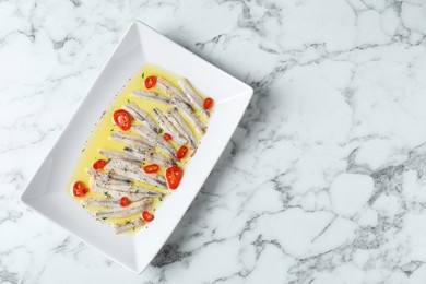 Tasty pickled anchovies with spices on white marble table, top view. Space for text