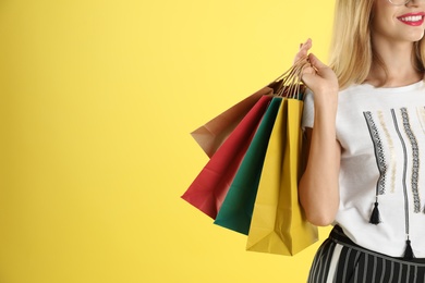 Photo of Young woman with shopping bags on color background, closeup. Space for text