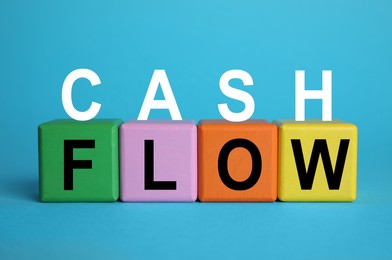 Phrase Cash Flow made with letters and colorful cubes on light blue background