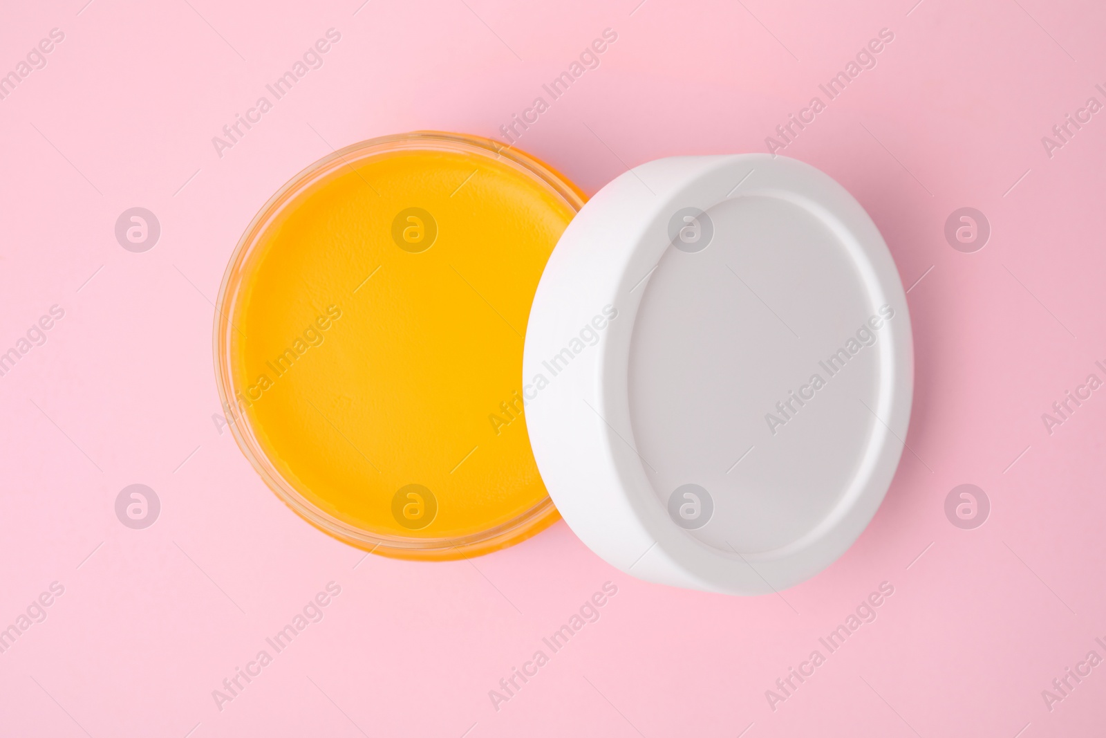 Photo of Open jar with petrolatum on pink background, top view