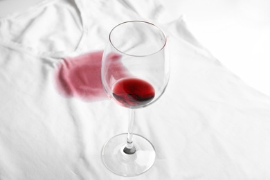 Photo of Transparent glass and spilled exquisite red wine on white t-shirt