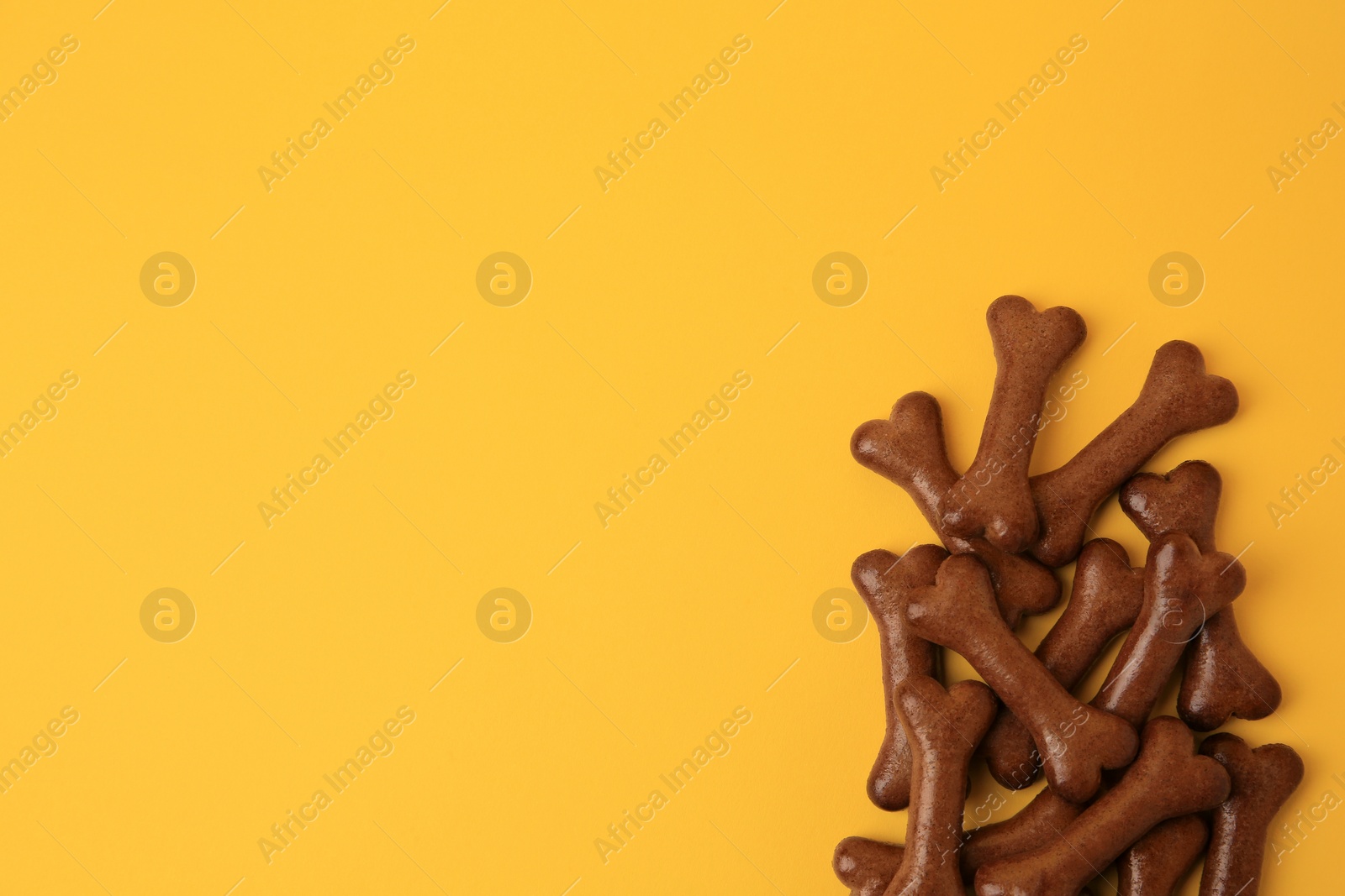 Photo of Bone shaped dog cookies on orange background, flat lay. Space for text