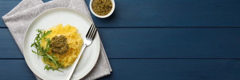 Tasty spaghetti squash with pesto sauce and arugula served on blue wooden table, flat lay. Banner design with space for text