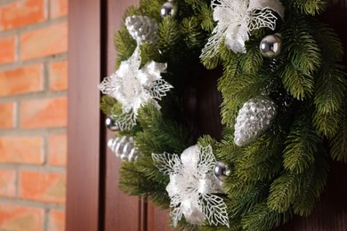 Photo of Beautiful Christmas wreath with festive decor hanging on wooden door, closeup. Space for text