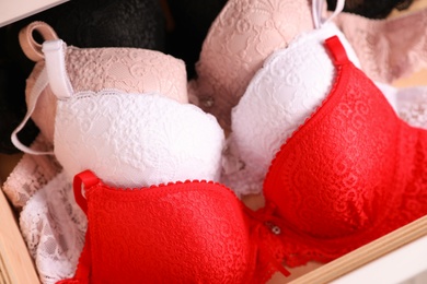 Photo of Drawer with beautiful lace bras, closeup. Stylish underwear