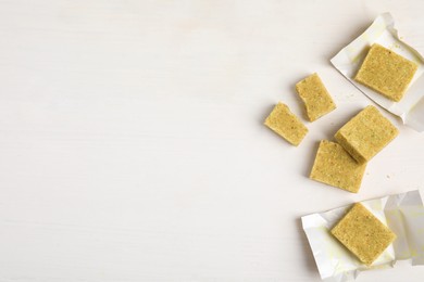 Photo of Bouillon cubes on white wooden table, flat lay. Space for text